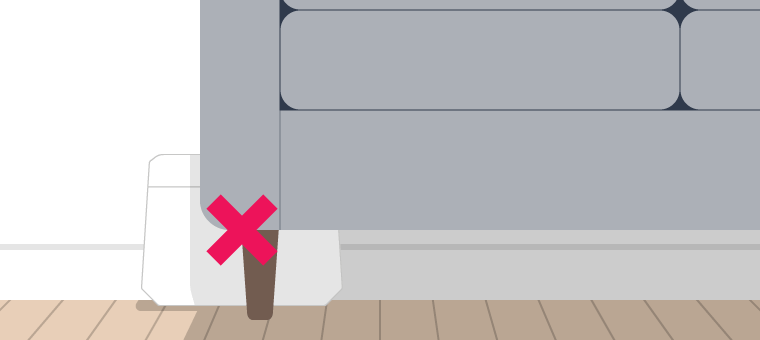 Billede af en router, som er placeret på gulvet bag en sofa.